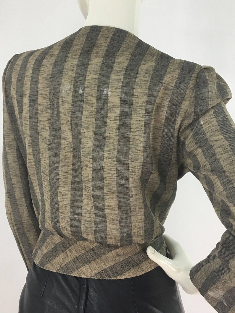 Puede incluir: Una camisa de manga larga a rayas marrones y negras con cuello en V. La camisa tiene un corte holgado y est&aacute; hecha de una tela ligera.