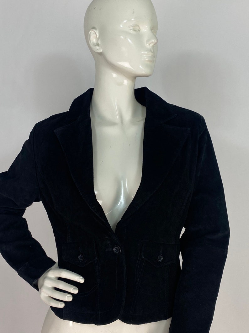 May include: A black velvet blazer with a notched collar, two front pockets, and a single button closure.