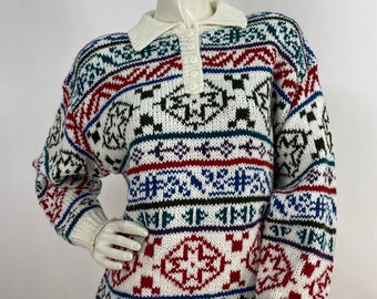 May include: A white knit sweater with a colorful geometric pattern in red, blue, green, and black. The sweater has a cream-colored collar and cuffs, and a three-button placket. The sweater is displayed on a mannequin.