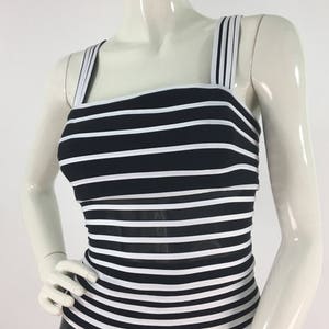 May include: Black and white striped sleeveless top with a square neckline and thin straps. The top is made of a stretchy fabric and has a fitted silhouette.