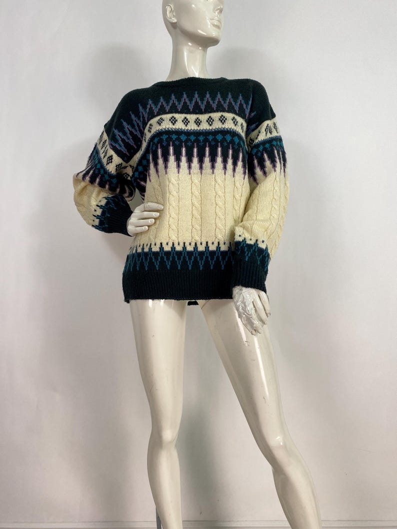 Pode incluir: Um su&eacute;ter preto e creme com um design de tric&ocirc; tran&ccedil;ado. O su&eacute;ter tem gola redonda e mangas compridas.