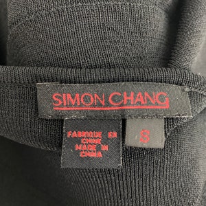 K&ouml;nnte beinhalten: Schwarzes Strickoberteil mit einem roten "SIMON CHANG"-Etikett und einem Gr&ouml;&szlig;enetikett "S". Das Etikett tr&auml;gt au&szlig;erdem die Aufschrift "Fabrique en Chine" und "Made in China".