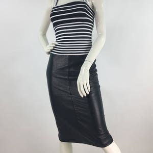 May include: A black leather skirt with a white and black striped tank top.