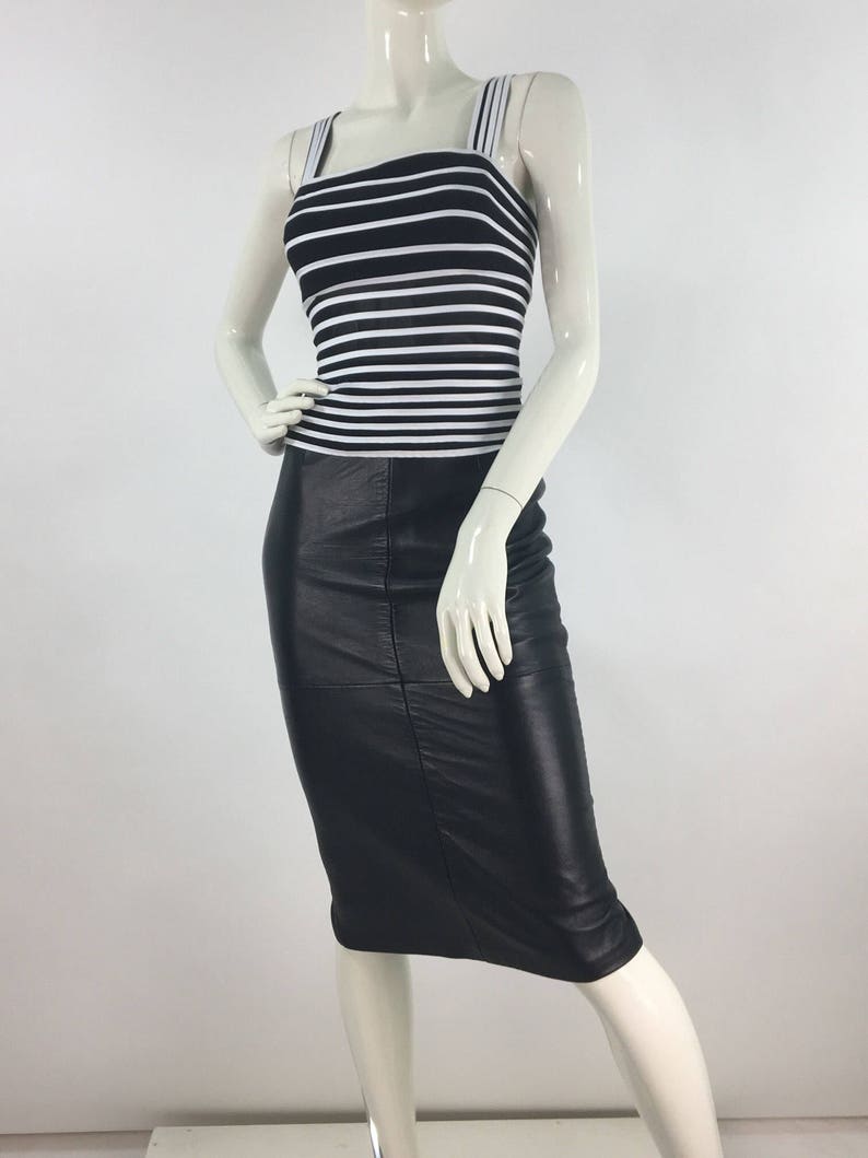 May include: A black leather skirt with a white and black striped tank top.