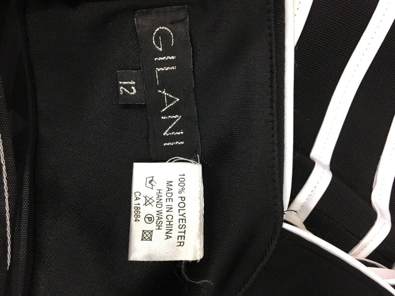 May include: Black and white striped athletic jacket with a white label that says "GLAN" and "100% POLYESTER MADE IN CHINA HAND WASH CA 18684"