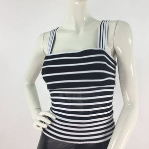 May include: A black and white striped tank top with thin straps. The top is made of a stretchy material and has a fitted silhouette.