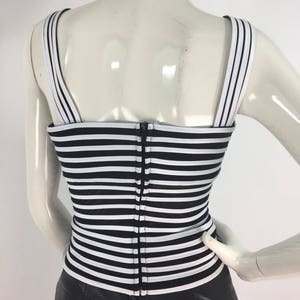 May include: Black and white striped sleeveless top with a zipper closure in the back. The top is made of a stretchy fabric and has a fitted silhouette.