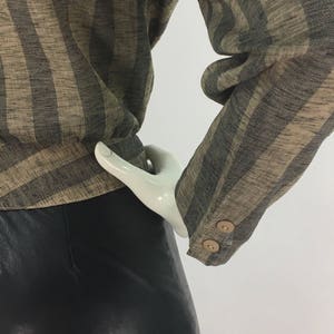 Puede incluir: Una camisa de manga larga a rayas marrones y negras con dos botones en el pu&ntilde;o. La camisa est&aacute; hecha de una tela suave y tejida.