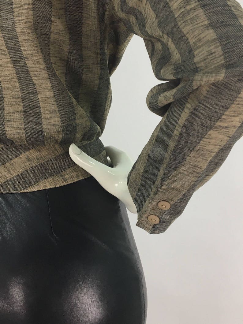 Puede incluir: Una camisa de manga larga a rayas marrones y negras con dos botones en el pu&ntilde;o. La camisa est&aacute; hecha de una tela suave y tejida.