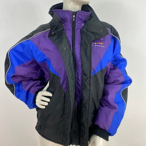 May include: A black, blue and purple winter jacket with a zip and snap fastening. The jacket has a hood and a logo that says "Mustang" on the front.