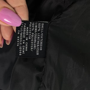 May include: A black leather jacket with a black label that reads "SHELL/EXTERIEUR: 100% LEATHER/CUIR LINING/DOUBLURE: 100% POLYESTER/POLYESTER MADE IN CHINA FABRIQUE EN CHINE STYLE/MODELE: 10946 CA 45376"