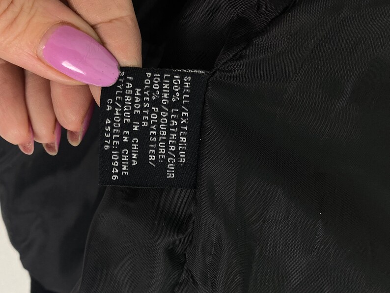 May include: A black leather jacket with a black label that reads "SHELL/EXTERIEUR: 100% LEATHER/CUIR LINING/DOUBLURE: 100% POLYESTER/POLYESTER MADE IN CHINA FABRIQUE EN CHINE STYLE/MODELE: 10946 CA 45376"