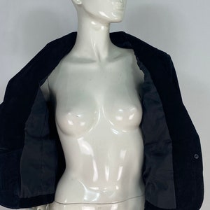 May include: A black velvet blazer with a single button fastening. The blazer is unbuttoned and the lining is visible.