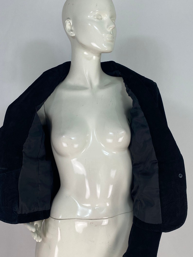 May include: A black velvet blazer with a single button fastening. The blazer is unbuttoned and the lining is visible.