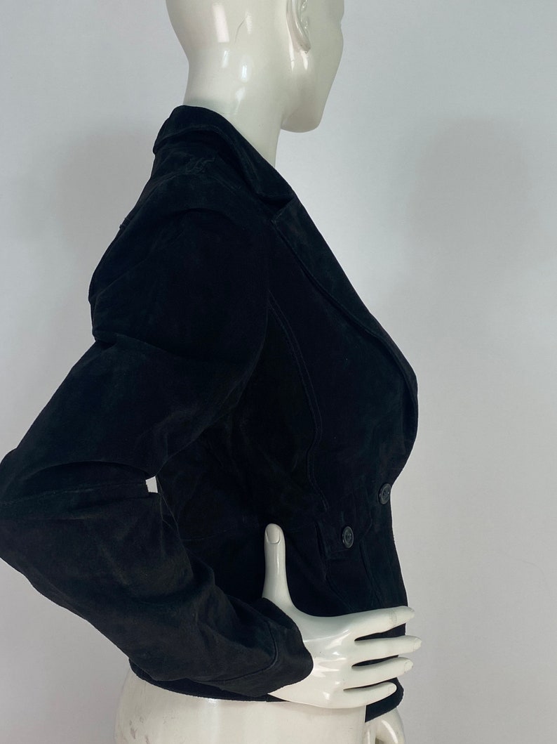 May include: A black suede jacket with a double-breasted closure and long sleeves.