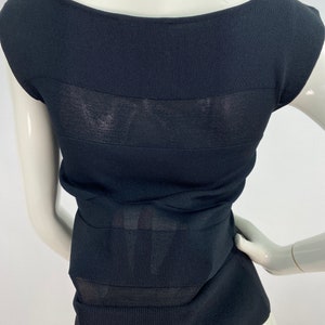 K&ouml;nnte beinhalten: Schwarzes &auml;rmelloses Oberteil mit einem transparenten Paneelelement. Das Oberteil ist aus geripptem Strickstoff.