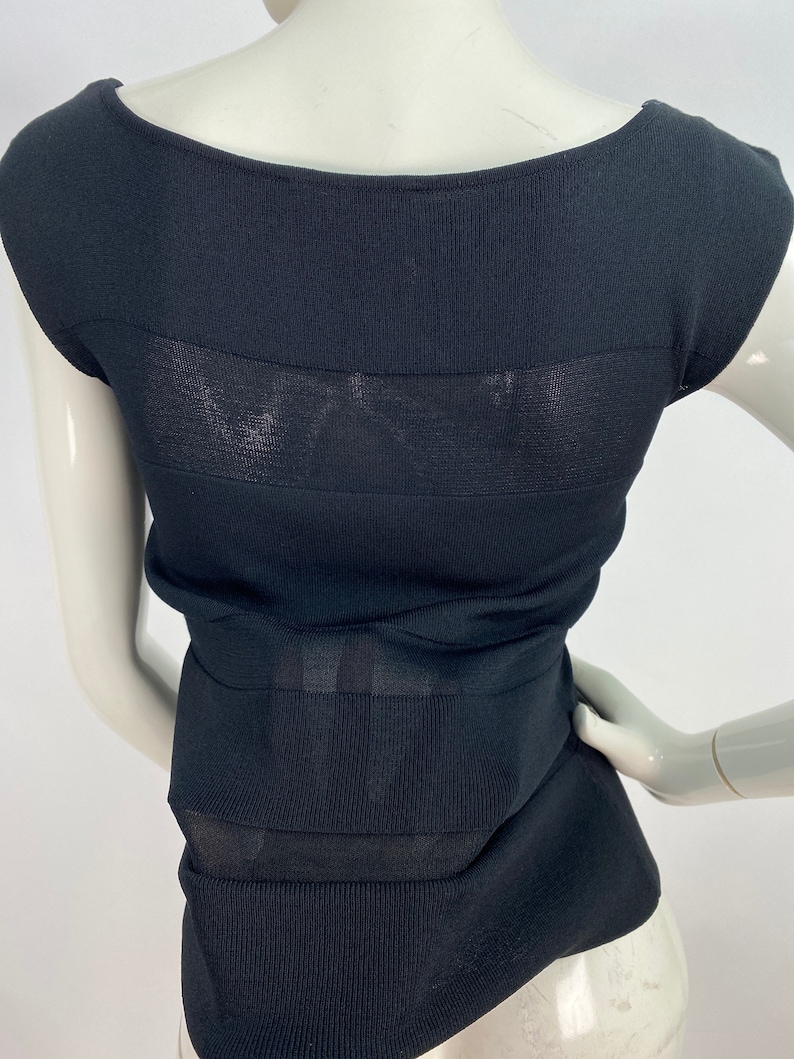 K&ouml;nnte beinhalten: Schwarzes &auml;rmelloses Oberteil mit einem transparenten Paneelelement. Das Oberteil ist aus geripptem Strickstoff.