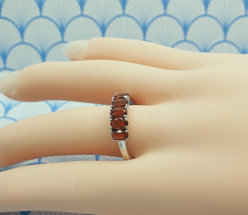 Puede incluir: Un anillo de plata con una fila de piedras preciosas marrones ovaladas.