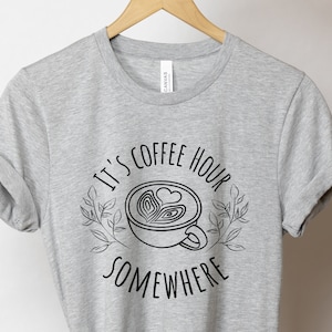 May include: Gray t-shirt with a black graphic of a coffee cup with the text "It's coffee hour somewhere".