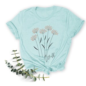 May include: A light blue t-shirt with a graphic of stylized flowers and the word "wild" printed on the front.