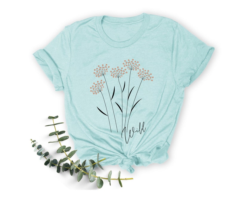 May include: A light blue t-shirt with a graphic of stylized flowers and the word "wild" printed on the front.