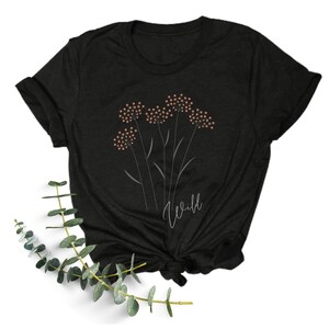 May include: Black t-shirt with a graphic of a cluster of pink flowers and the word "wild" in white script.