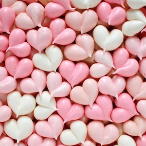 May include: A close-up image of a collection of pink and white heart-shaped meringue cookies.
