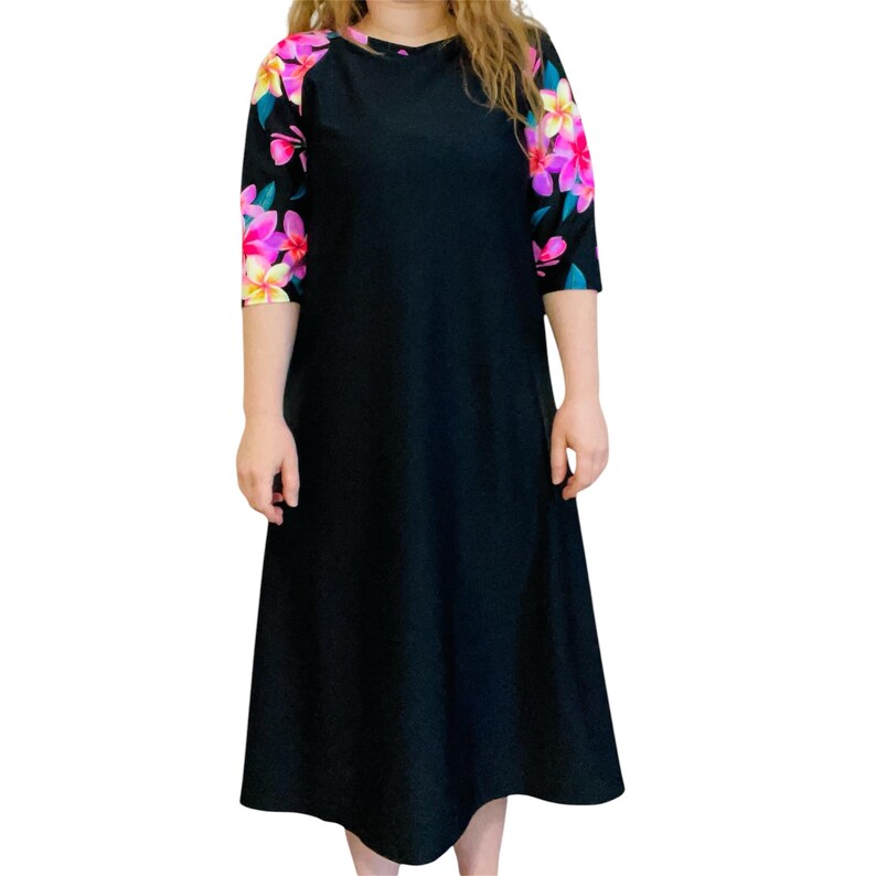 Puede incluir: Un vestido midi negro con estampado floral en las mangas. Las mangas son de tres cuartos y el vestido tiene un escote redondo.