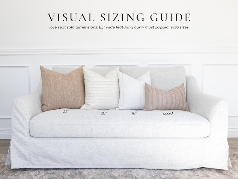 Puede incluir: Un sof&aacute; de dos plazas gris claro con cuatro cojines decorativos de varios tama&ntilde;os. El texto dice: VISUAL SIZING GUIDE, love seat sofa dimensions: 85" wide featuring our 4 most popular sofa sizes, 22", 20", 18" y 12x20 pulgadas.