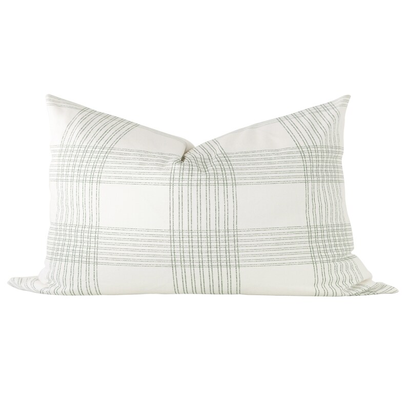 May include: A rectangular throw pillow featuring a white base color with a subtle, thin-lined plaid pattern in a muted sage green. The design consists of intersecting vertical and horizontal lines forming a grid across the entire surface.