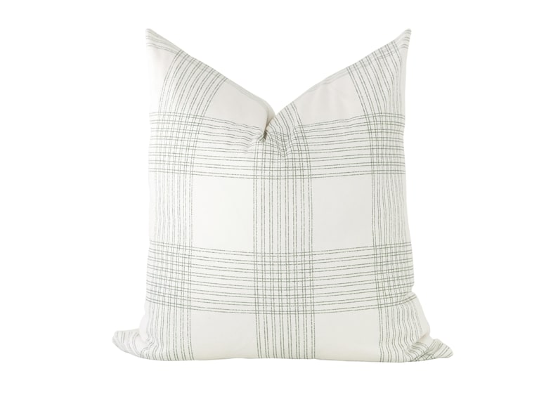May include: A square throw pillow featuring a white base fabric with a subtle grey plaid pattern. The design consists of thin, intersecting grey lines forming a grid across the surface, creating a clean and structured appearance on the pillow cover.