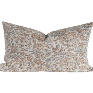 May include: A rectangular throw pillow featuring an off-white base fabric with a repeating floral pattern in muted shades of peach, tan, and charcoal gray. The design consists of stylized blossoms and leafy vines covering the entire surface.