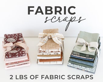 May include: Three stacks of fabric scraps, each tied with a ribbon. The stacks are arranged on a white surface. The text "FABRIC scraps" is written above the stacks. The text "2 LBS OF FABRIC SCRAPS" is written below the stacks.