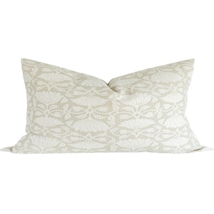 May include: A beige pillow with a white floral pattern. The pillow is made of a soft, textured fabric.