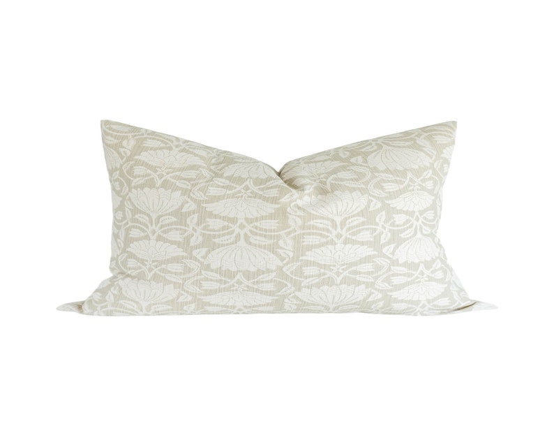 May include: A beige pillow with a white floral pattern. The pillow is made of a soft, textured fabric.