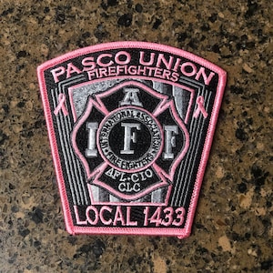 May include: Pink and black embroidered patch with the text "Pasco Union Firefighters Local 1433" and a black and white firefighter's emblem with the letters "IAFF" and "AFL-CIO CLC".
