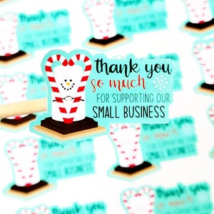May include: A turquoise blue sticker featuring a cartoon marshmallow wearing a candy cane hat. The sticker reads "Thank you so much for supporting our small business".