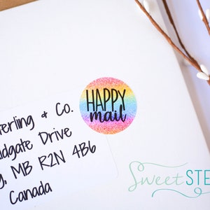 May include: A white envelope with a colorful "HAPPY MAIL" sticker. The sticker is a circle with a rainbow glitter design. The envelope also has the address "Sweet Sterling + Co., 492 Aldgate Drive, Winnipeg, MB R2N 4B6, Canada."