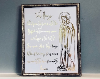 Könnte beinhalten: Ein goldfarbener gerahmter Druck mit weißem Hintergrund und goldenen Schriftzügen. Der Druck zeigt eine Silhouette von Maria, der Mutter Jesu, mit dem Text "Gegrüßet seist du, Maria, voll der Gnade, der Herr ist mit dir. Du bist gebenedeit unter den Frauen, und  gebegnedet ist die Frucht deines Leibes, Jesus. Heilige Maria, Mutter Gottes, bitte für uns Sünder, jetzt und in der Stunde unseres Todes. Amen."