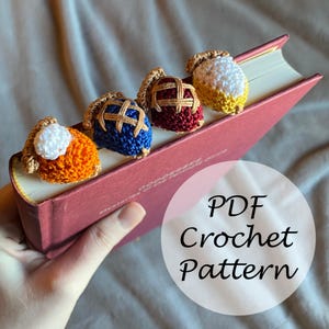 May include: Four crocheted pie bookmarks in different colors and designs. The bookmarks are on a red book with the text "PDF Crochet Pattern".