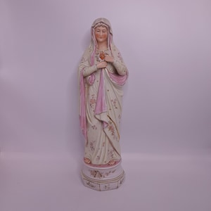 Puede incluir: Una estatua de porcelana de la Virgen Mar&iacute;a con una t&uacute;nica rosa y blanca y un dise&ntilde;o floral. Ella sostiene un coraz&oacute;n en sus manos.