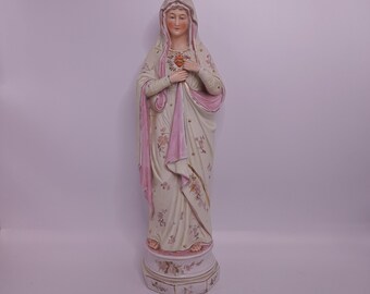 Könnte beinhalten: Eine Porzellanstatue der Jungfrau Maria mit einem rosa-weißen Gewand und einem Blumendesign. Sie hält ein Herz in ihren Händen.