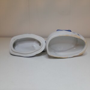 May include: Two white ceramic containers with blue and white floral designs. The containers are open and empty, revealing the white interior.