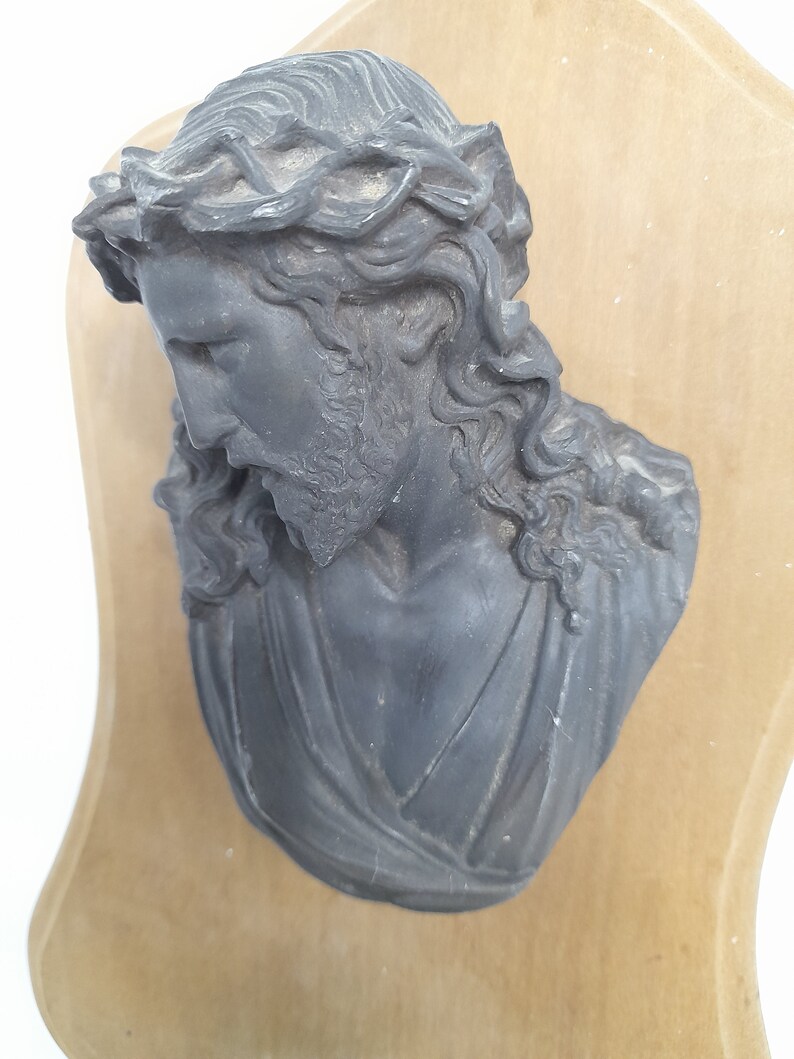 K&ouml;nnte beinhalten: Eine schwarze Gipsb&uuml;ste von Jesus Christus mit einer Dornenkrone auf einer Holztafel.