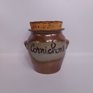 May include: A brown ceramic jar with a cork lid and the word "Cornichons" written on the side.