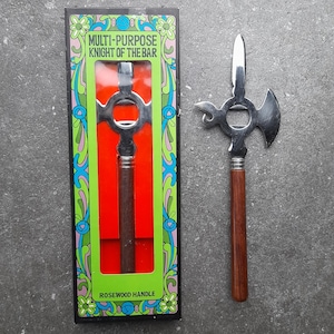 Könnte beinhalten: Ein Mehrzweck-Bar-Werkzeug, der "Knight of the Bar", mit einem Kopf aus Edelstahl und einem Rosenholzgriff. Das Werkzeug wird in seiner Originalverpackung präsentiert, die den Text "Multi-Purpose Knight of the Bar" und "Rosewood Handle" trägt.