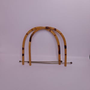 Pode incluir: Duas alças de bambu marrom e preto com pontas de metal dourado. As alças são conectadas por uma fina barra de metal dourado.