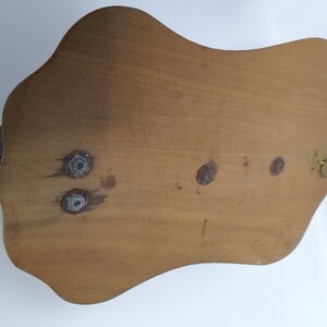 K&ouml;nnte beinhalten: Die R&uuml;ckseite einer Wandplakette aus Holz mit einem dekorativen Design. Die Plakette hat vier Schraubenl&ouml;cher und einen kleinen Metallring zum Aufh&auml;ngen.