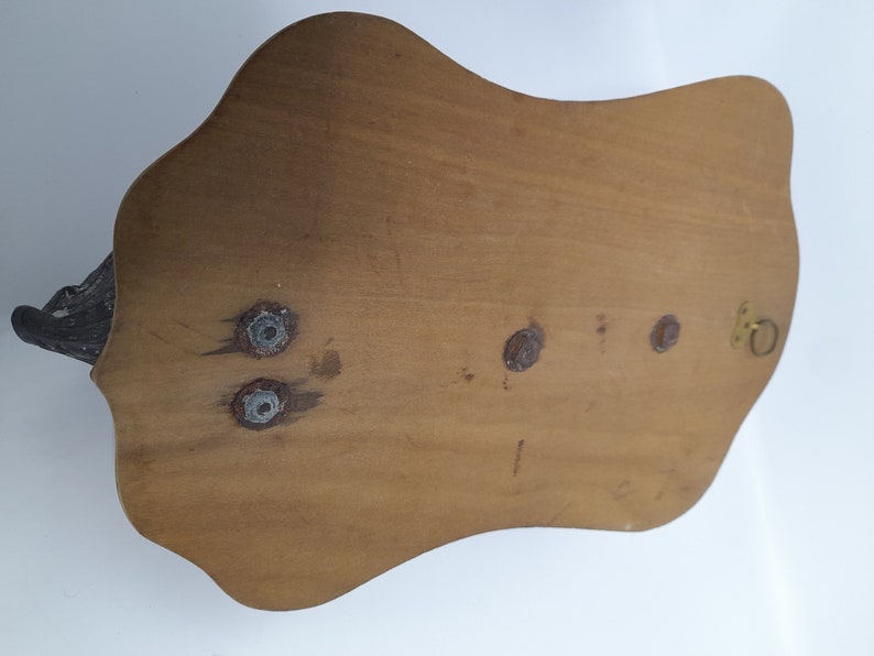 K&ouml;nnte beinhalten: Die R&uuml;ckseite einer Wandplakette aus Holz mit einem dekorativen Design. Die Plakette hat vier Schraubenl&ouml;cher und einen kleinen Metallring zum Aufh&auml;ngen.