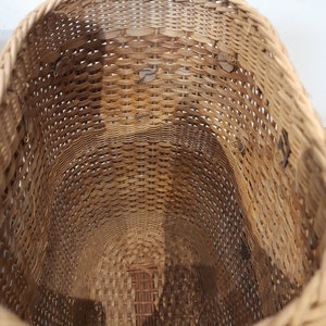 May include: A woven wicker basket with a round opening. The basket is made of natural brown wicker and has a smooth, even weave.